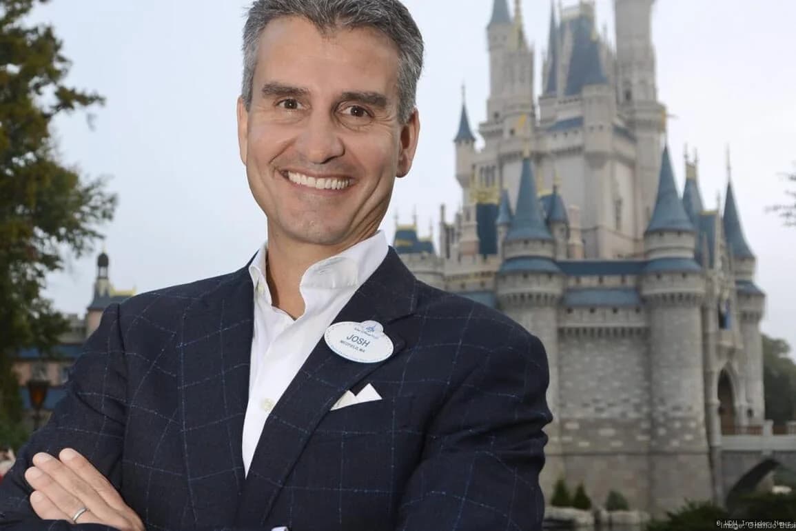 Disney executives in a meeting room discussing digital platform plans on a conference table with laptops and documents
