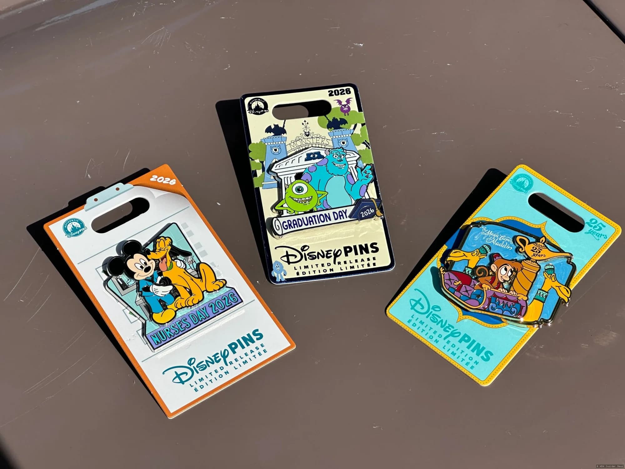 A display of three commemorative Disney pins featuring Magic Carpets anniversary designs and special occasion artwork