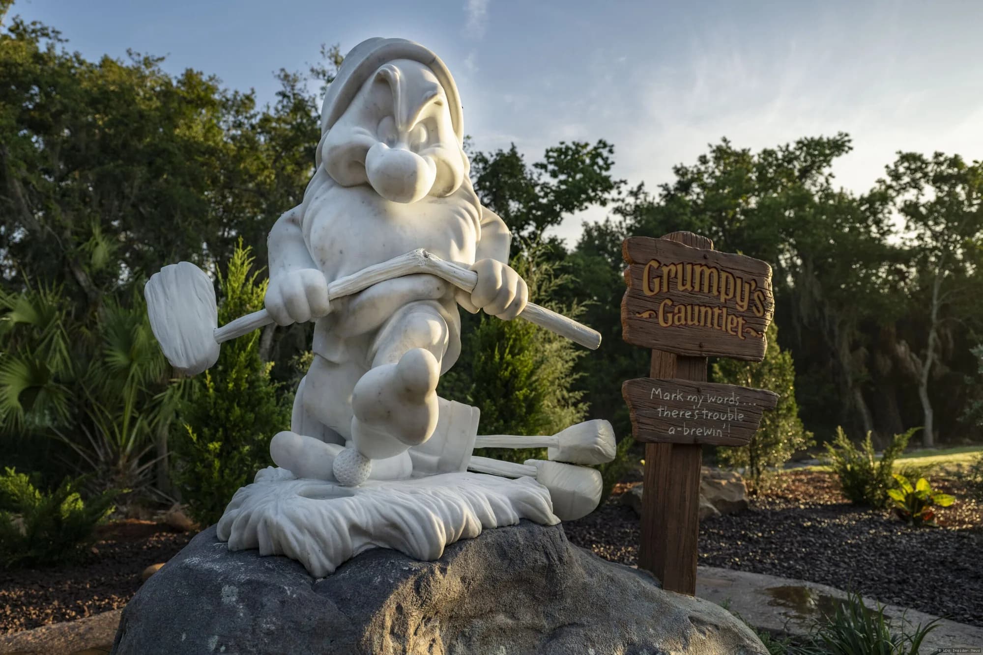 Six-foot bronze statue of Grumpy the dwarf standing on the Magnolia Golf Course at Walt Disney World, marking a…