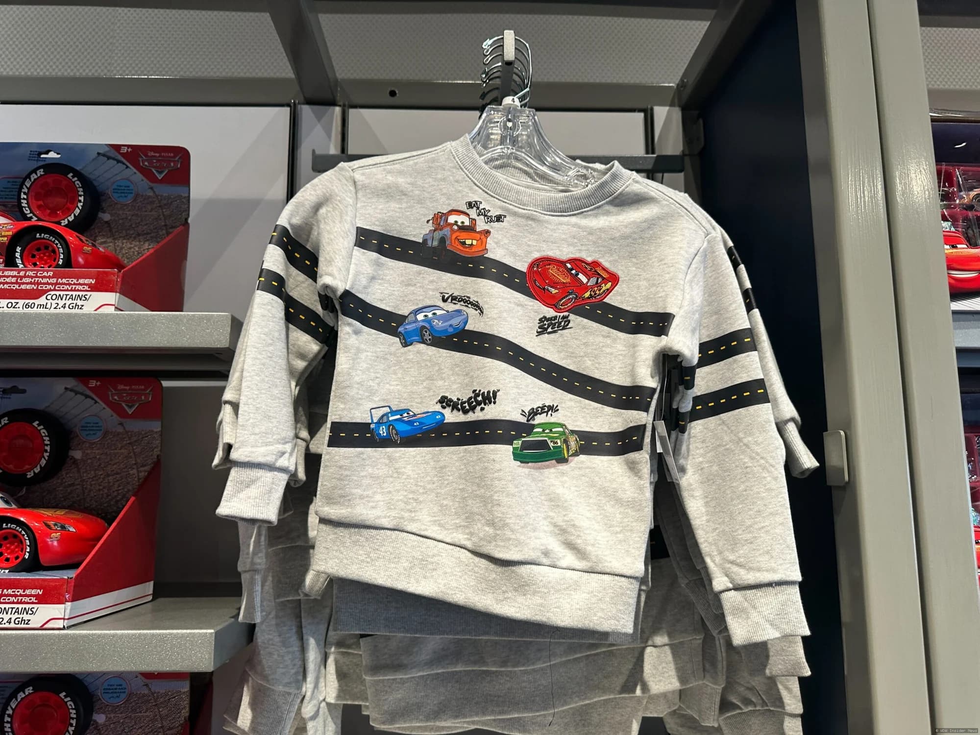 Lightning McQueen youth clothing displayed on mannequins or hanging in a Disney Springs or EPCOT retail shop
