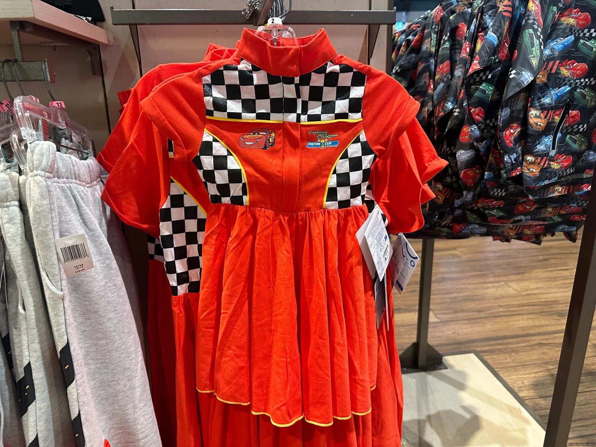 Lightning McQueen youth clothing displayed on mannequins or hanging in a Disney Springs or EPCOT retail shop