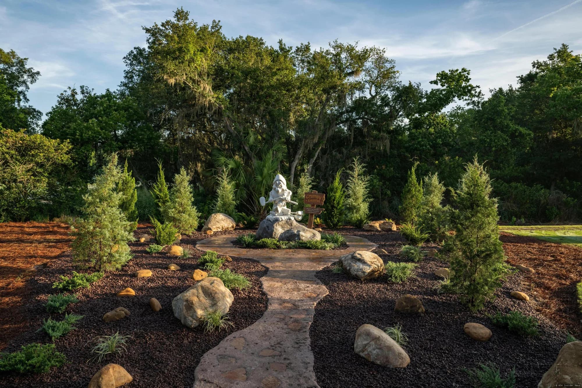 Six-foot bronze statue of Grumpy the dwarf standing on the Magnolia Golf Course at Walt Disney World, marking a…