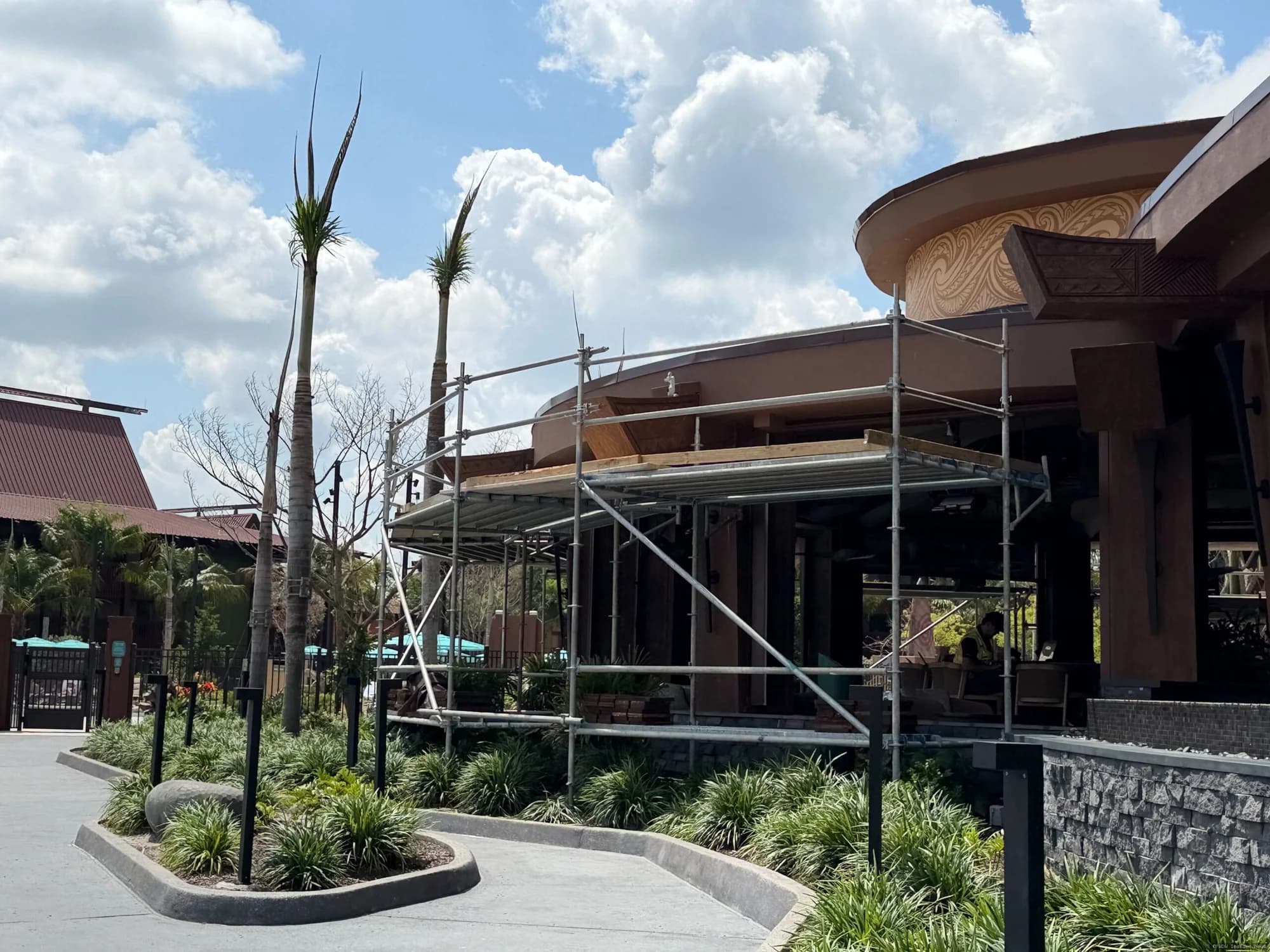 Outdoor bar area at Wailulu with Polynesian-style thatched roof during daytime, partially obscured by construction barriers