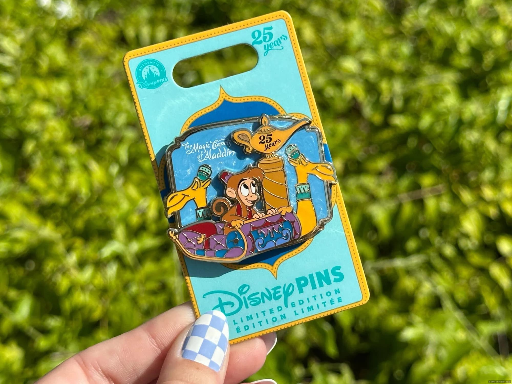 A display of three commemorative Disney pins featuring Magic Carpets anniversary designs and special occasion artwork