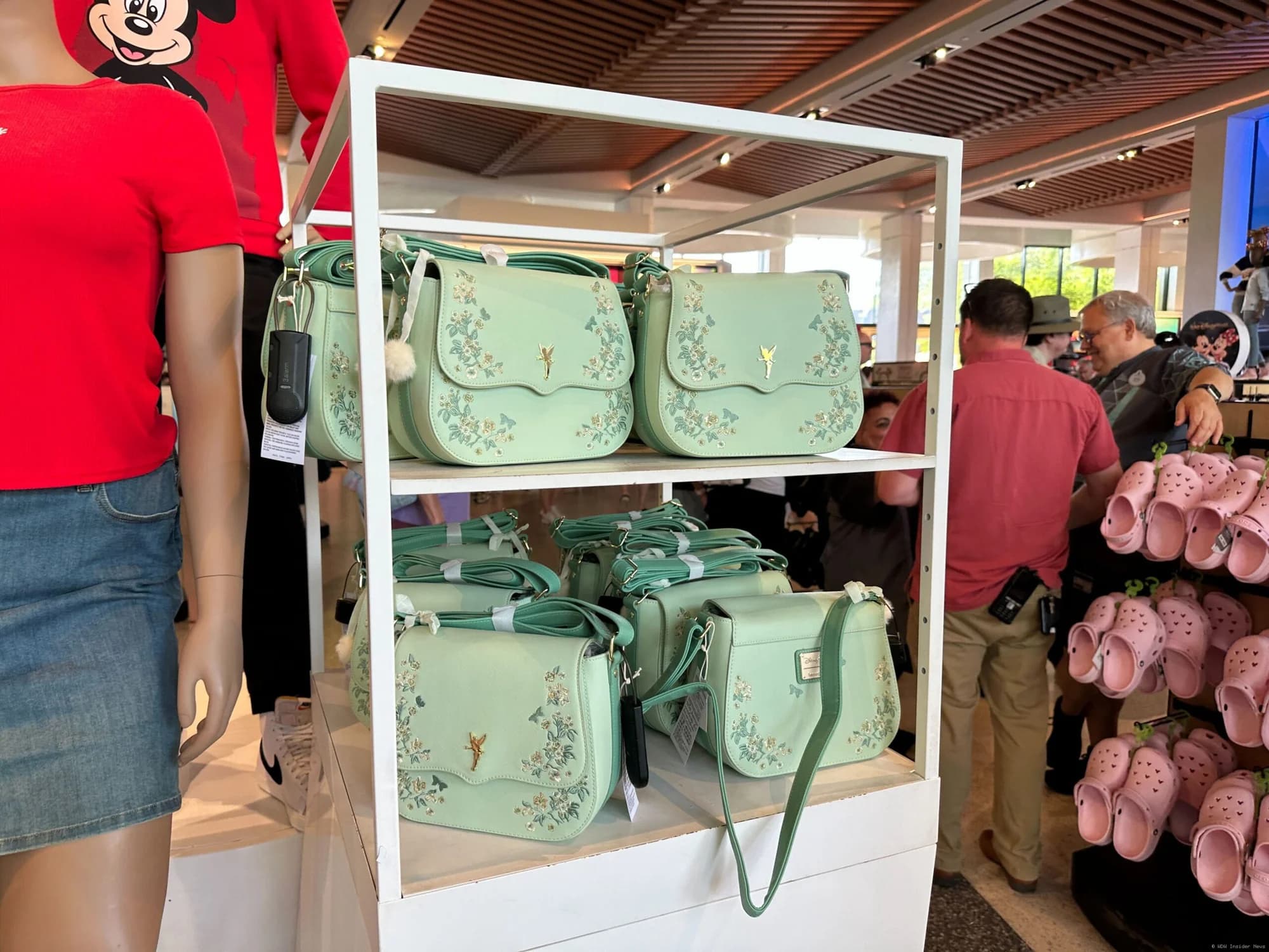 Ornate Mickey Mouse and Tinker Bell designer handbags displayed on a retail shelf at Disney World