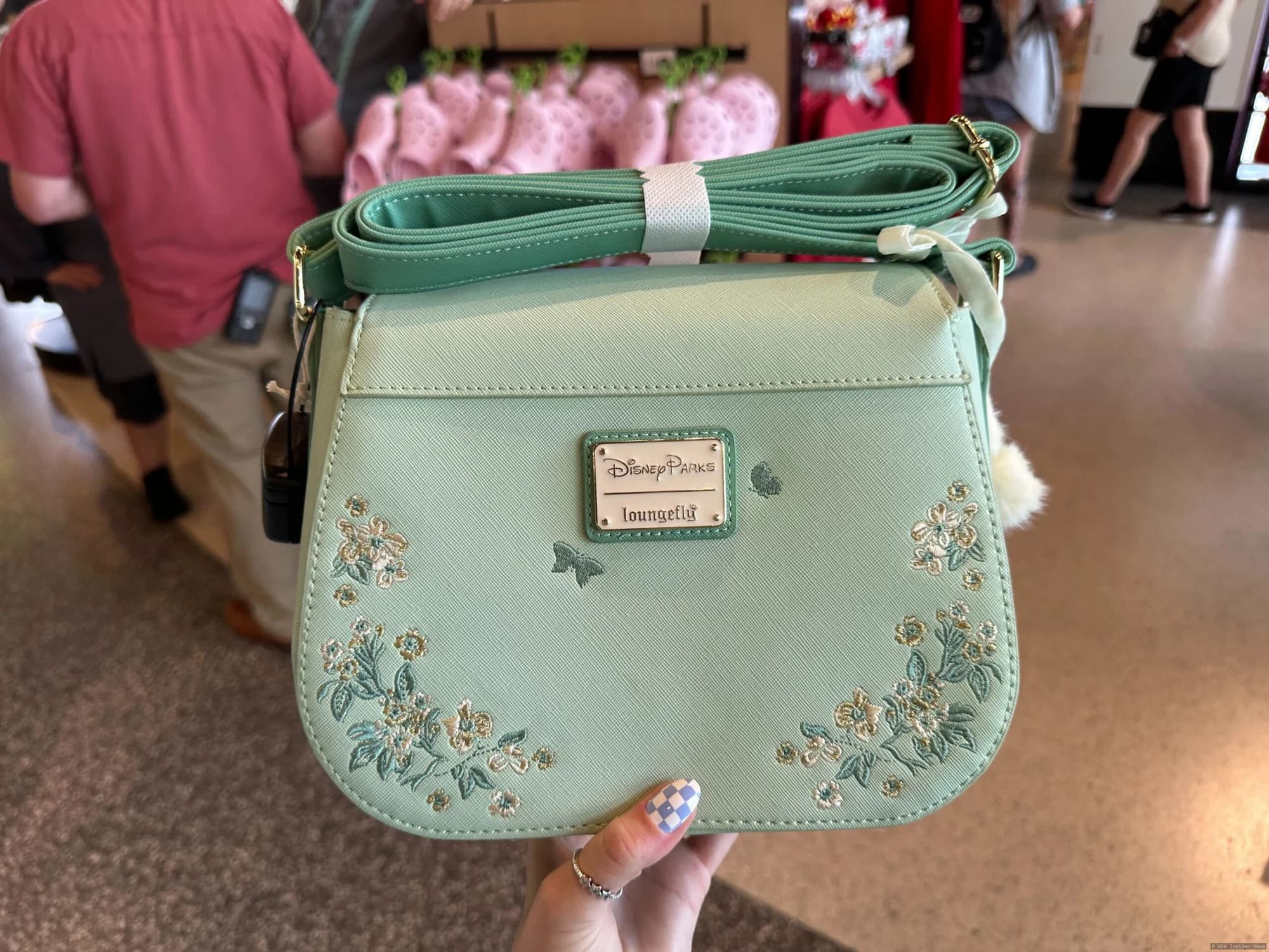 Ornate Mickey Mouse and Tinker Bell designer handbags displayed on a retail shelf at Disney World