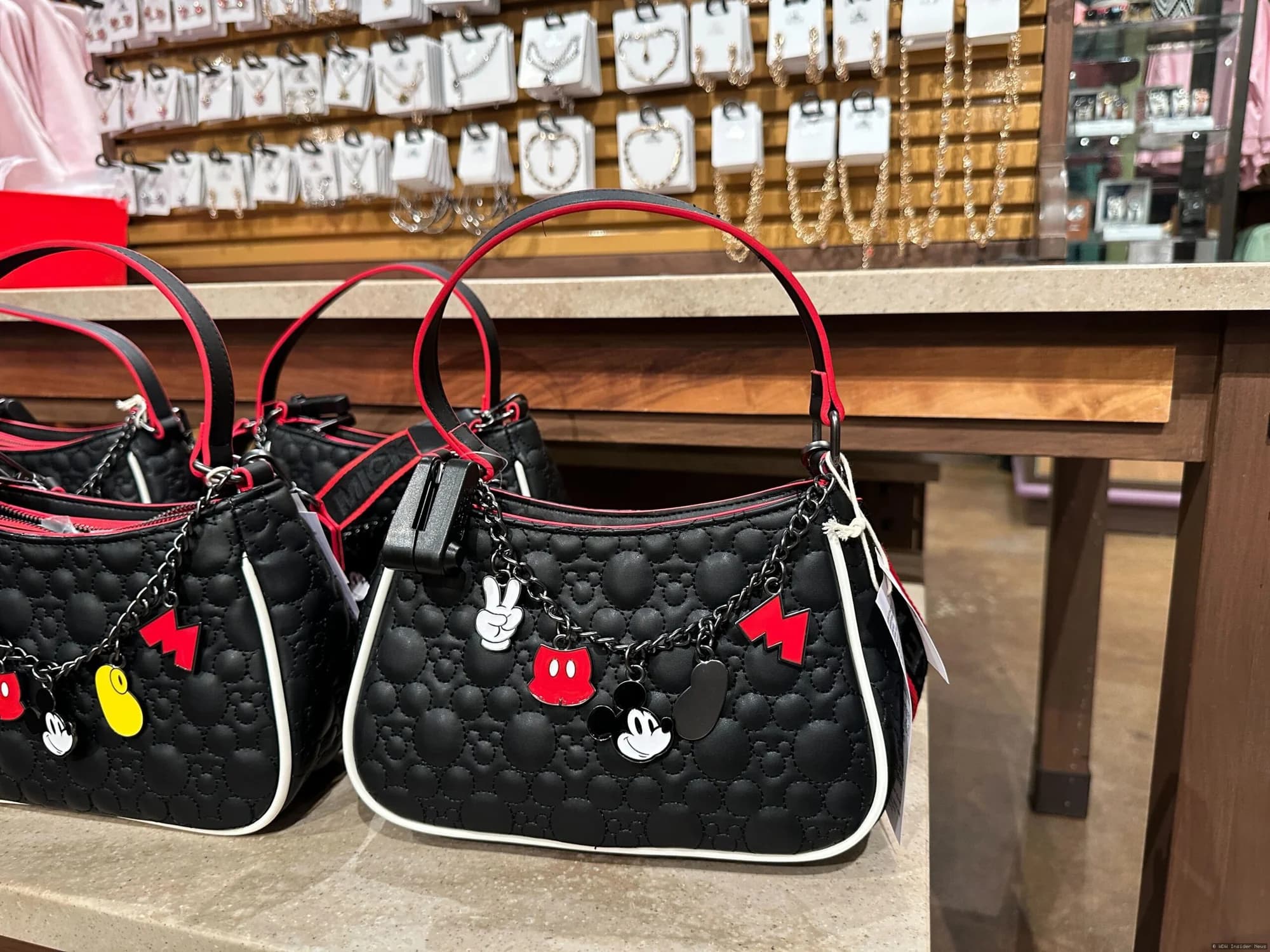 Ornate Mickey Mouse and Tinker Bell designer handbags displayed on a retail shelf at Disney World