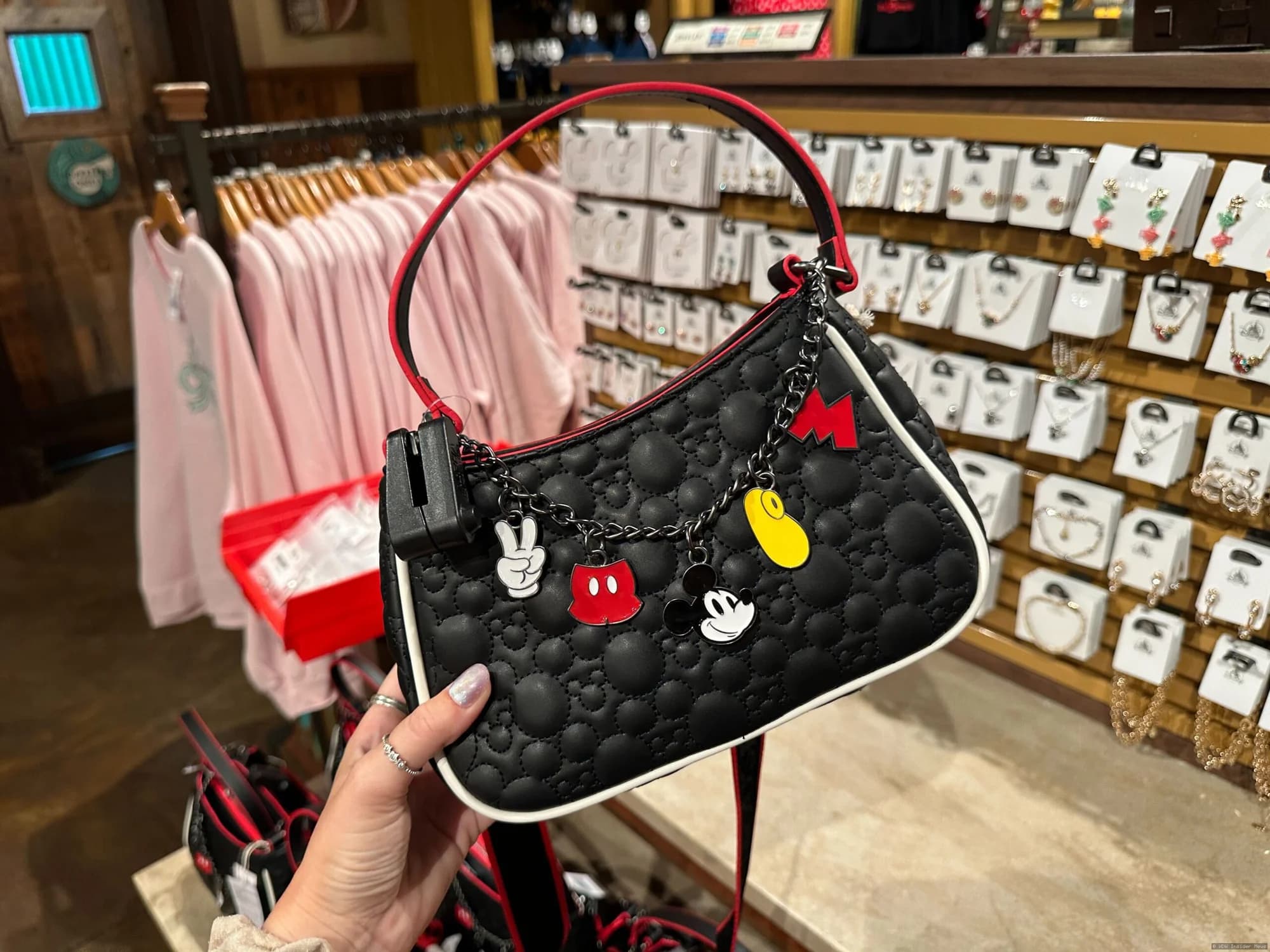 Ornate Mickey Mouse and Tinker Bell designer handbags displayed on a retail shelf at Disney World
